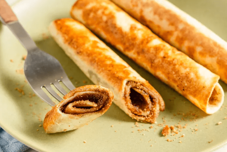 Family hands reaching for crispy cinnamon-sugar tortilla roll-ups on a tray