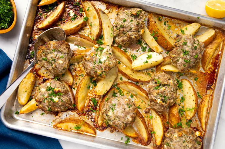 Sheet pan biftekia with lemony potato wedges topped with fresh herbs and lemon wedges