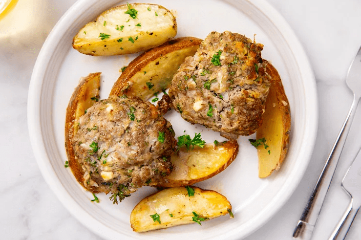 Finished sheet pan biftekia and golden lemony potato wedges with fresh herbs