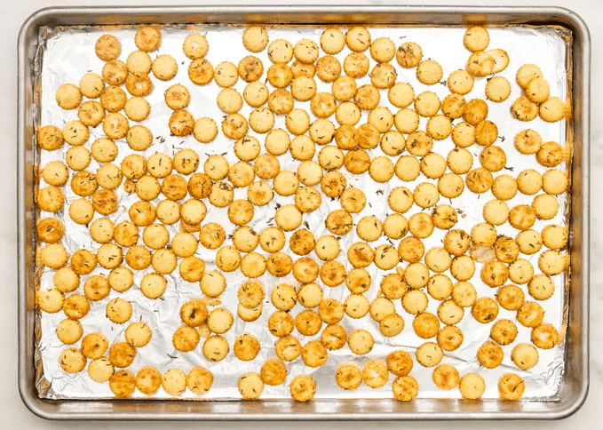 Seasoned oyster crackers baked until golden brown on a lined baking sheet for topping chicken pot pie soup