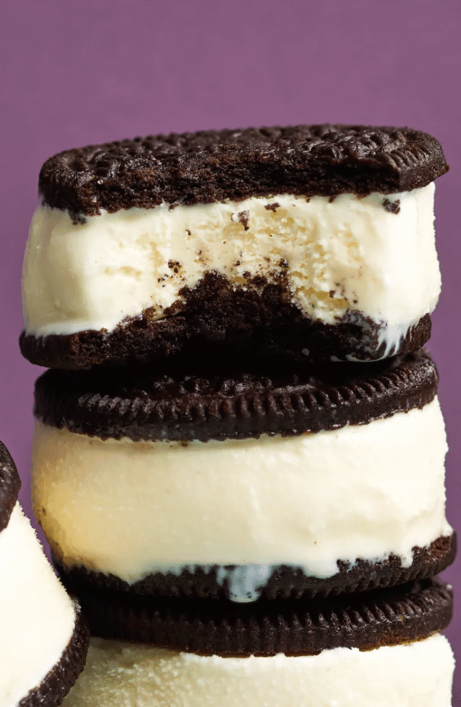 Sandwich cookies, a pint of premium ice cream, and a bowl of finished two ingredient ice cream sandwiches