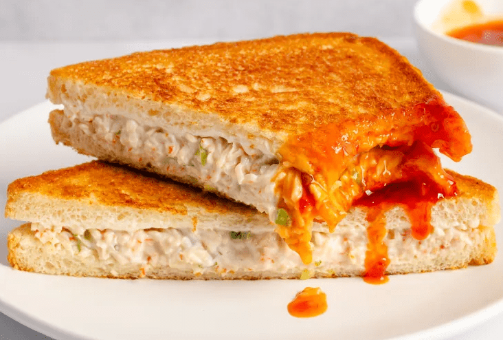 Close up of a crab Rangoon sandwich showing creamy crab filling inside crisp golden bread