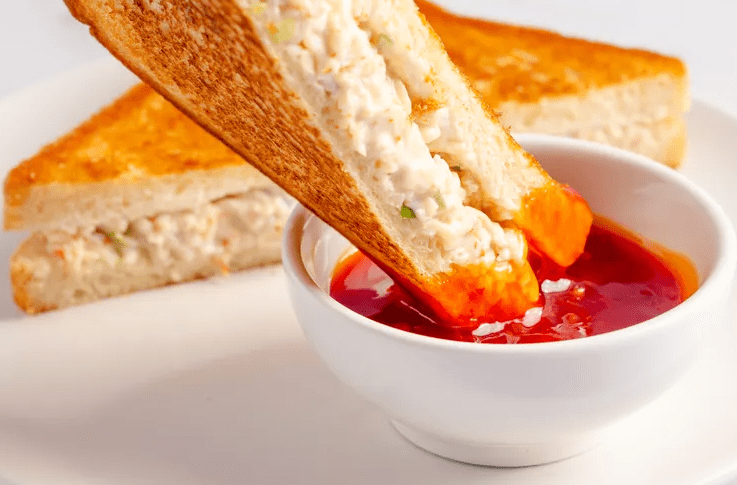 A crab Rangoon sandwich triangle from a shared platter with sweet chili dipping sauce