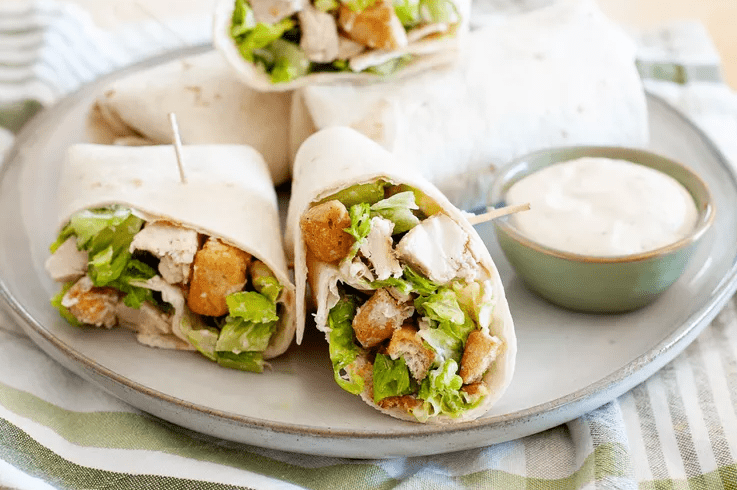 Family style plate of chicken Caesar wraps on a kitchen table 
