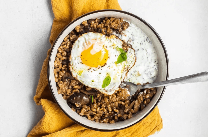 A farro mushroom and egg grain bowl with herb yogurt and fresh herbs is ready to serve