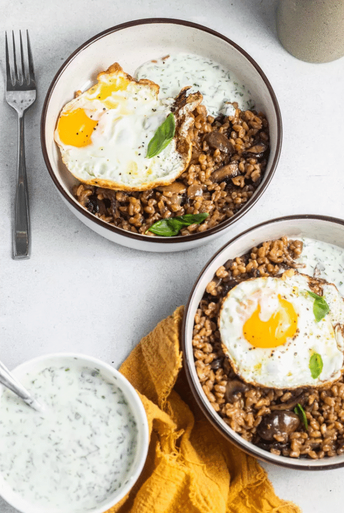 Table set with farro mushroom and egg grain bowls, extra herb yogurt, and fresh herbs ready to serve.