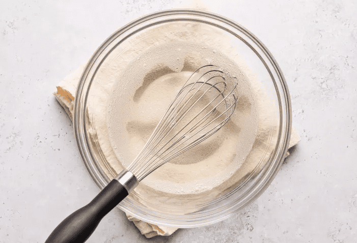 Unflavored gelatin dissolved in warm water in a glass bowl with whisk