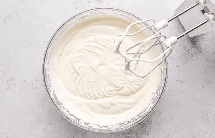 Softly whipped cream and condensed milk in a mixing bowl for creamy gelatin layer