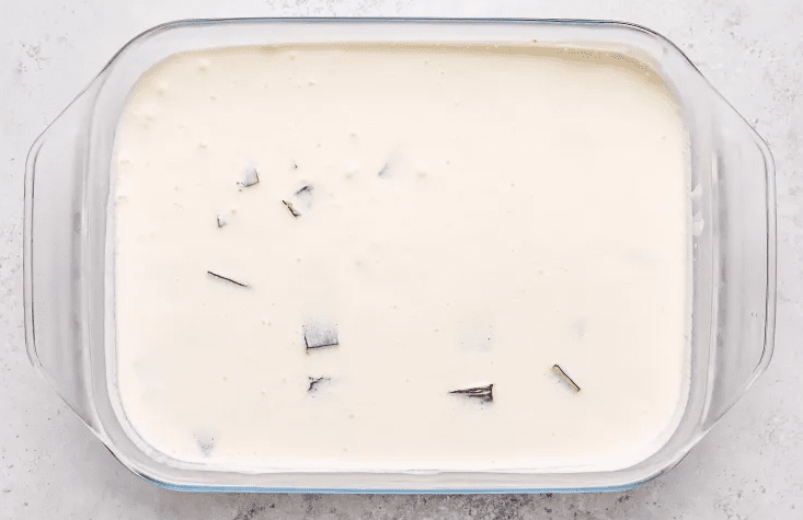 Creamy gelatin mixture poured over colorful gelatin cubes in a clear mold