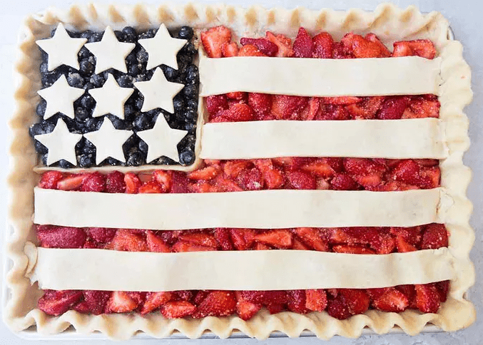 Whole American Flag Pie slab dessert on a sheet pan showing blueberry stars and strawberry stripes for a patriotic party