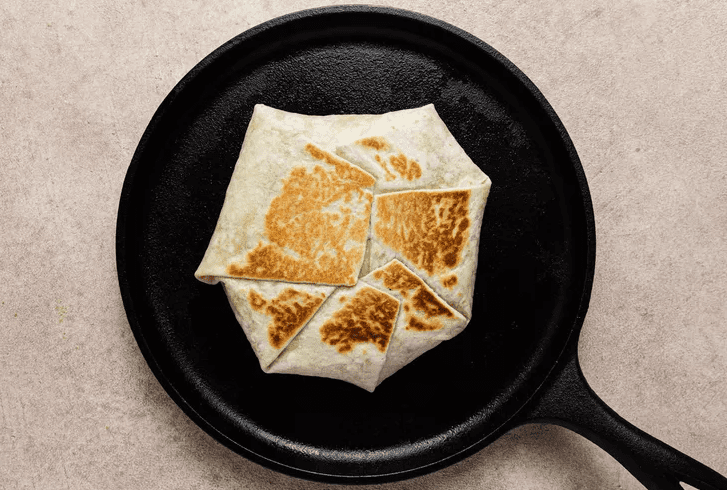 Crunchwrap Supreme searing seam-side down in a skillet until golden and crispy