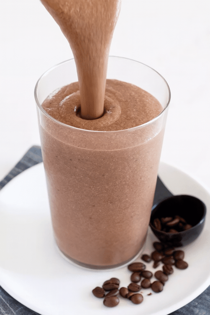 close view of the smoothie being poured in a thick ribbon into a glass filled almost to the top.