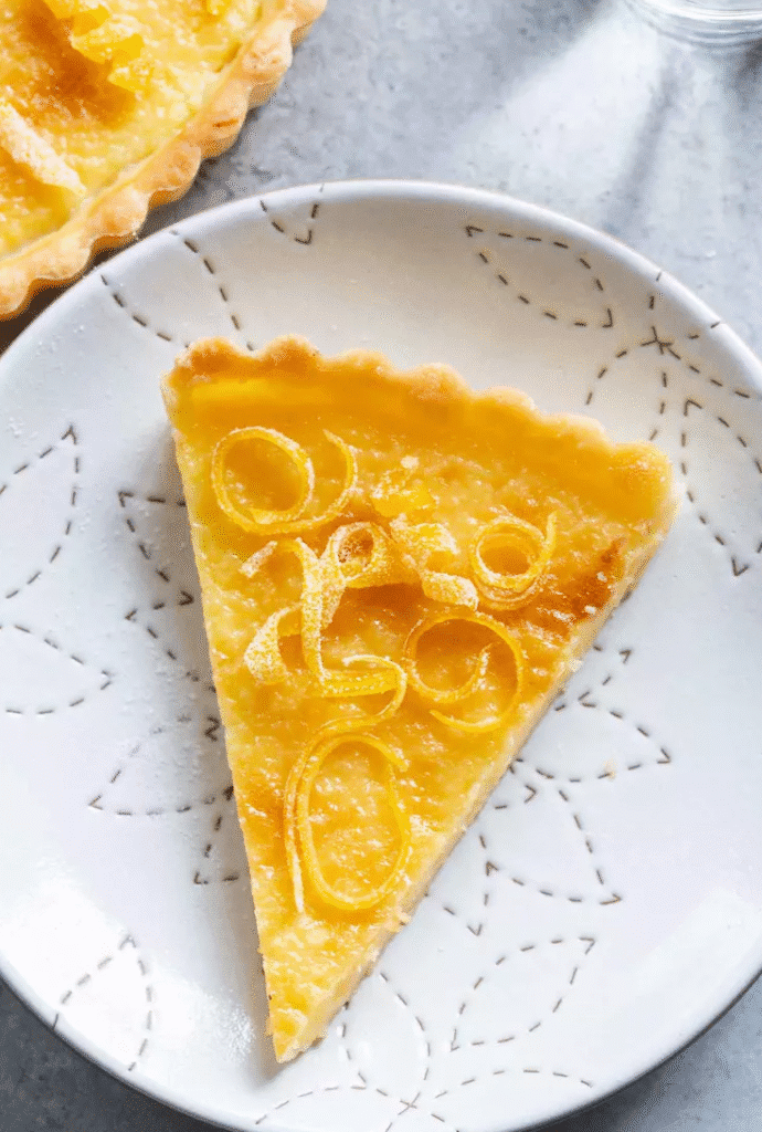 Sliced lemon tart showing smooth custard filling and crisp pastry crust on a dessert plate