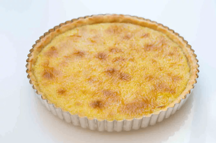 Lemon tart cooling on a rack and chilling in the refrigerator to set