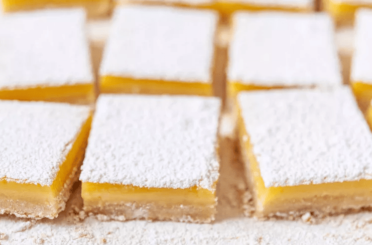 Close up of classic lemon bar showing layers of buttery crust and smooth lemon curd