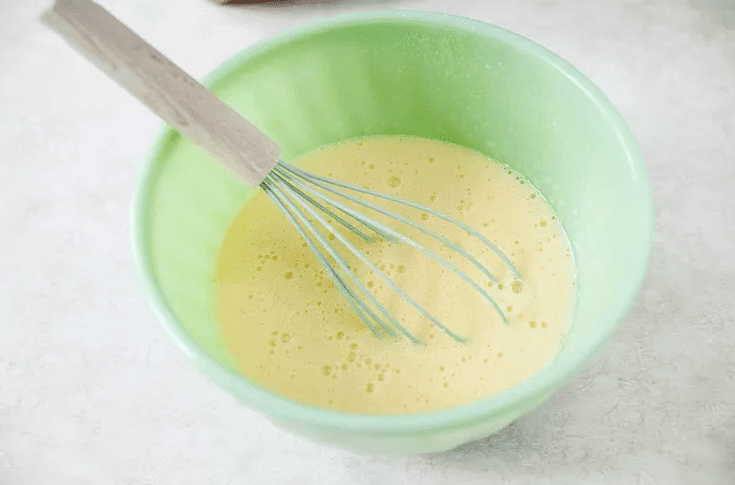 Whisking lemon bar filling with eggs sugar flour and fresh lemon juice in a mixing bowl
