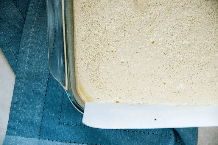 Classic lemon bars baked in oven with set lemon layer showing tiny surface bubbles