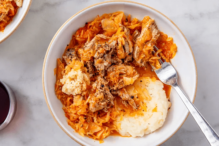 Plate of braised pork roast and sauerkraut served with mashed potatoes and horseradish ready to eat